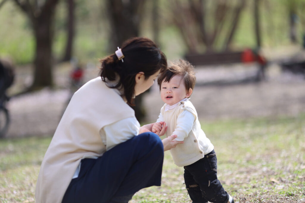 Young mother and son having fun under cherry blossoms