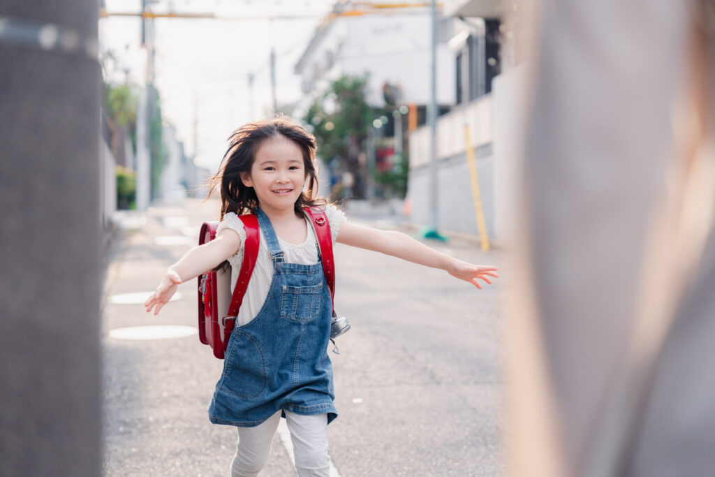 An elementary school girl running to her mother with her school bag on her back Japanese School System