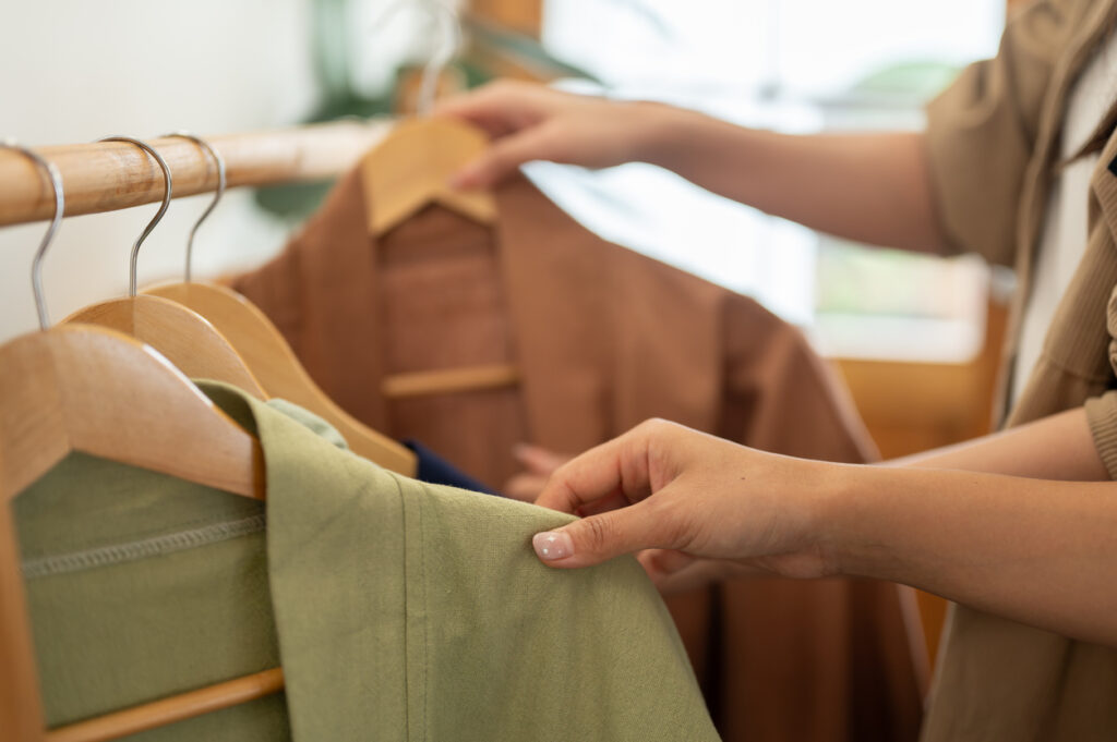 Why Choose Slow Fashion? A close-up of two female friends selecting clothes from a rack, enjoying their shopping experience together in a store. lifestyles, fashion, and people