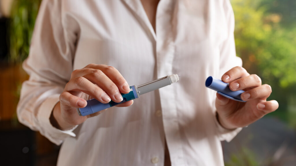 Woman in white shirt, standing in a rustic living room, is holding semaglutide injection pen in her hands. Ozempic in Japan