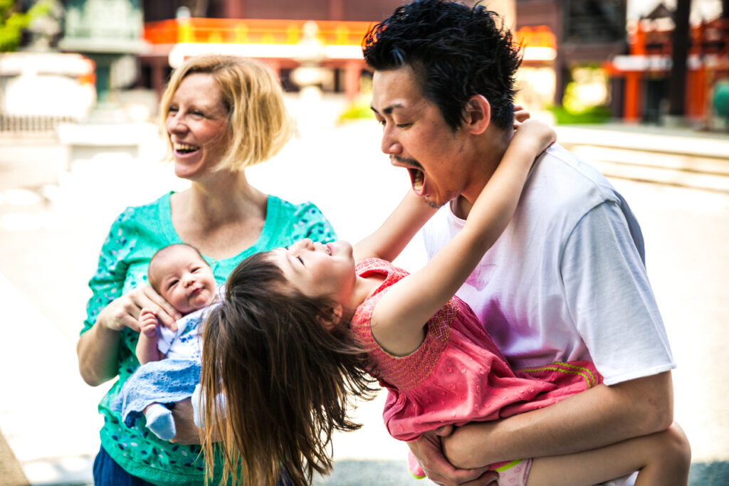 Happy family playing together in Kyoto, Japan. An interracial (japanese-english) family spending a day outdoor relaxing at the park.